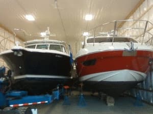 Two cruisers on stands inside the Coral Gables Yachts heated storage building.
